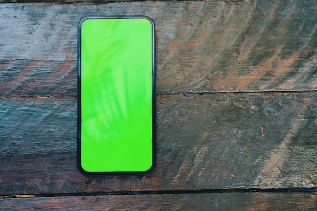 公園の素朴な木製テーブルのスマートフォン画面の緑色の画面上面図クロマキー