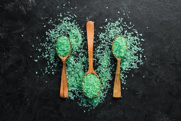 Green sea salt in a spoon On a black stone background Spa treatments