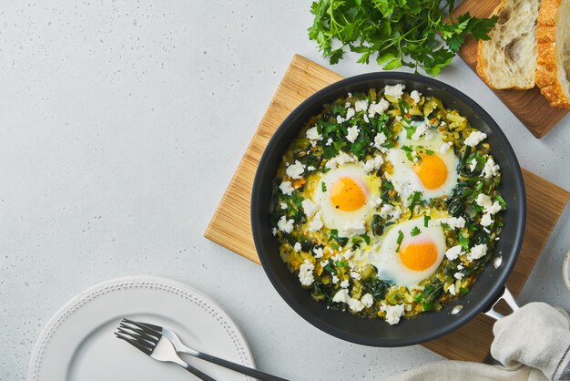 Green shakshouka with eggs spinach salty sheep milk cheese celery pepper and ciabatta