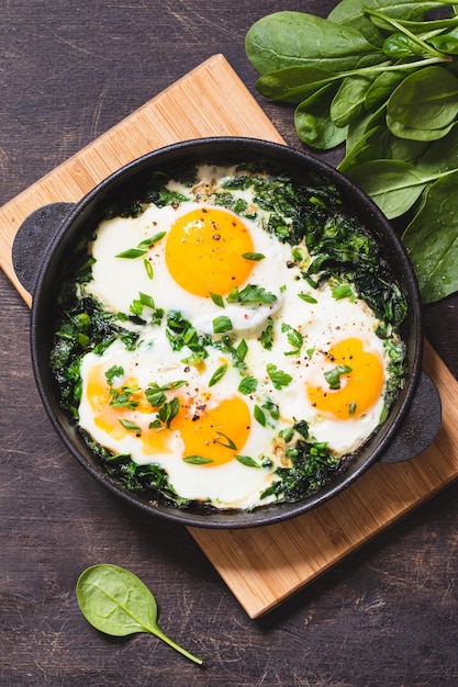 Shakshuka verde in una padella di ghisa uova fritte con spinaci e toast fritti colazione sana