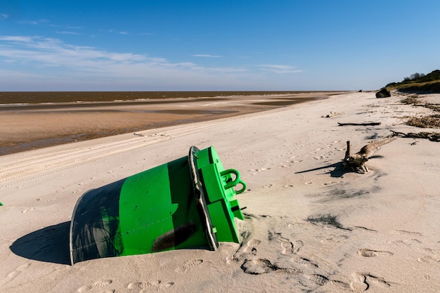 Green signaling beacon that ran aground on the beach Two other signaling beacons in the background