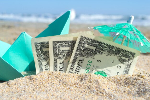 緑の小さな紙のボート半3ドル紙幣と紙のカクテル傘