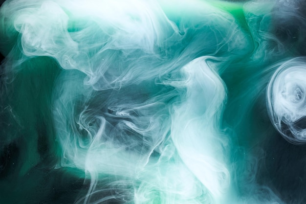 Fumo verde su sfondo di inchiostro nero, nebbia colorata, mare smeraldo vorticoso astratto, pigmento di vernice acrilica sott'acqua