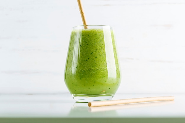 Green smoothie from spinach, apple, cucumber and soy milk in glass on white background