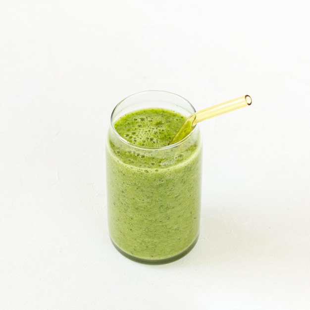 Green smoothie in glass on white background Vegan raw clean healthy food