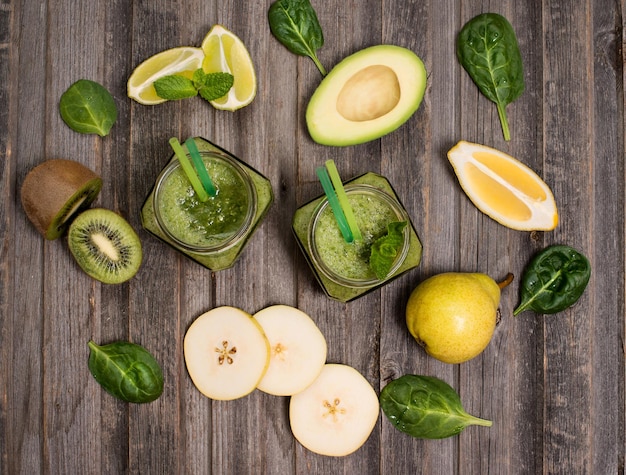 Green smoothie with avocado spinach lime kiwi and pear in a jar on rustic wooden background