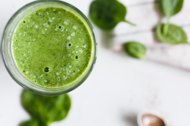 Green smoothie with banana and spinach fresh herbs on the background top view