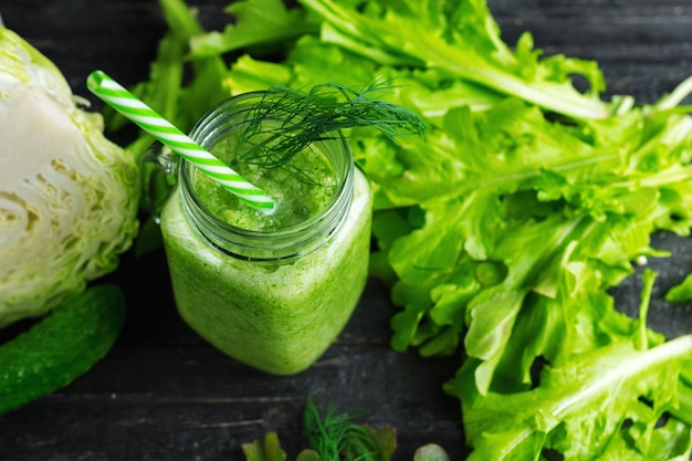 Green smoothie with cucumber, cabbage and healthy greens on the table