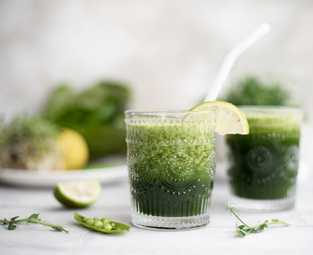 Green smoothie with fresh greens and lemon in glass