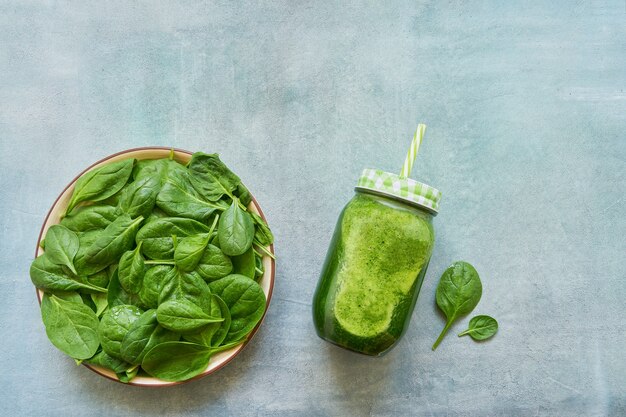 Green smoothie with spinach and kale in glass jar with straw copy space healthy food flat lay