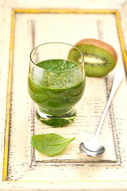 Green smoothie with spinach and kiwi on light vintage background