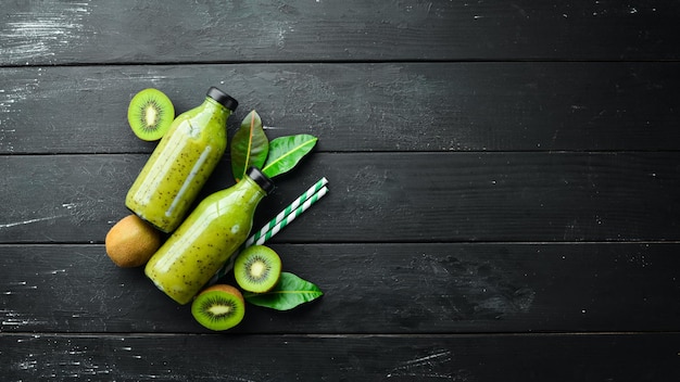 Green Smoothies with fresh kiwi and kiwi on a black background Wooden Rustic style Fruits Top view Free space for text