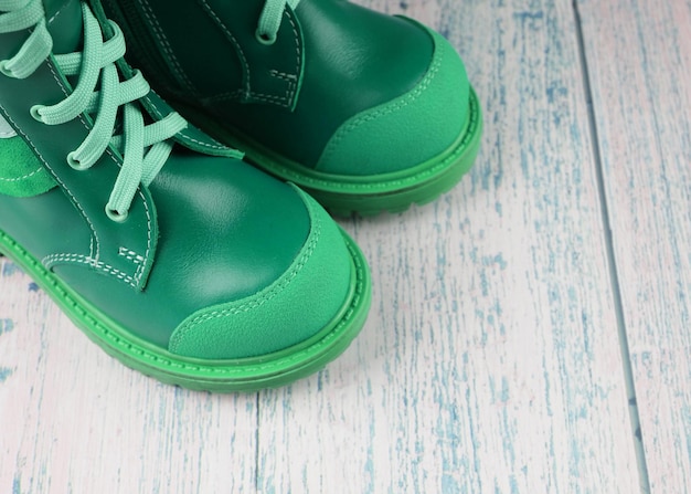 Зеленые кроссовки для ребенка на деревянном фоне, детская обувь, копия космоса.