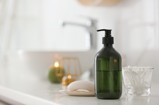 Green soap dispenser on white countertop in bathroom Space for text