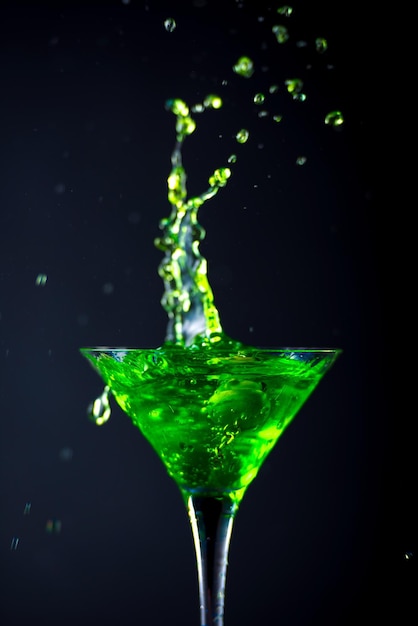 Green soft drink with splashing soda in a glass