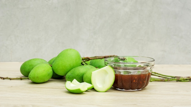 Green sour mango (raw mango) with sweet fish sauce on a wooden table.