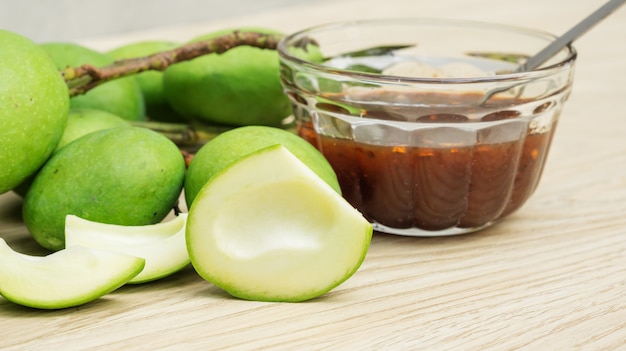 Green sour mango (raw mango) with sweet fish sauce on a wooden table.