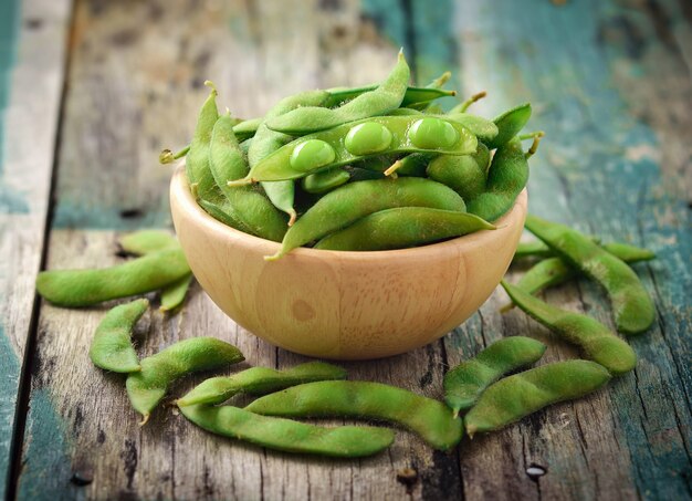 Photo green soy beans in the wooden bowl on table