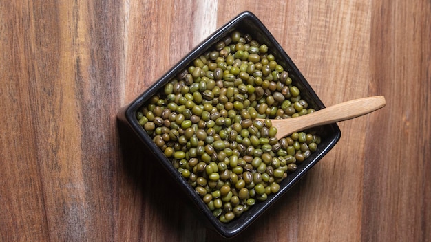 Green soybeans in square bowl with wooden spoon