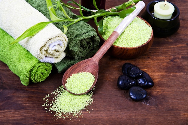 Green Spa tools with candle and towel on wood