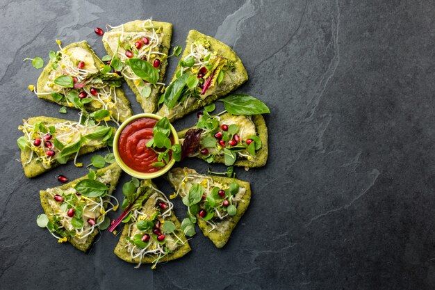 Green spinach dough, vegetables and cheese pizza, slate background