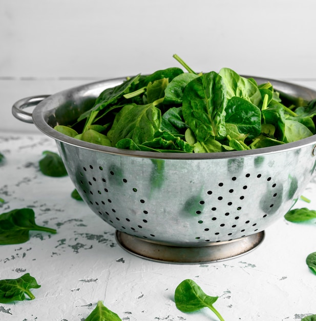 Green spinach leaves in an iron colander 