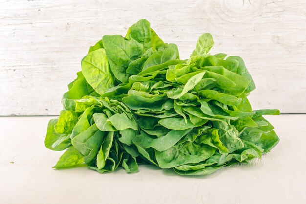 green spinach on white wooden background