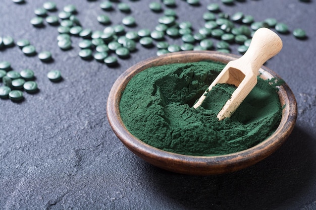 Photo green spirulina powder in bowl and pills nature medicine