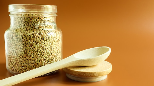 Green sprouts of raw organic buckwheat in a glass cereal jar with a wooden spoon. Vegan food concept. Organic food. The concept of diet, weight loss, healthy and proper nutrition. Copy space for text.