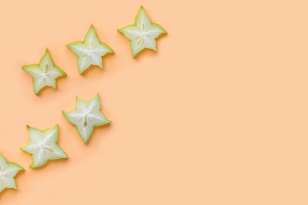 Green star fruit slices on pastel color background.