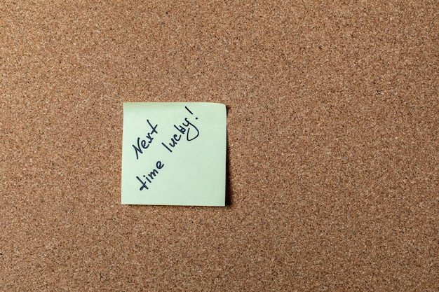 Green sticker on brown table. color sticker, motivational, quote, and words, note, message next time lucky!