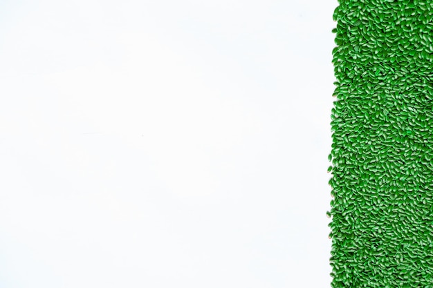 Фото Зеленая полоса окрашенных семян на белом фоне в качестве абстрактного фона