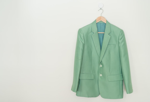 Photo green suit hanging with wood hanger on wall