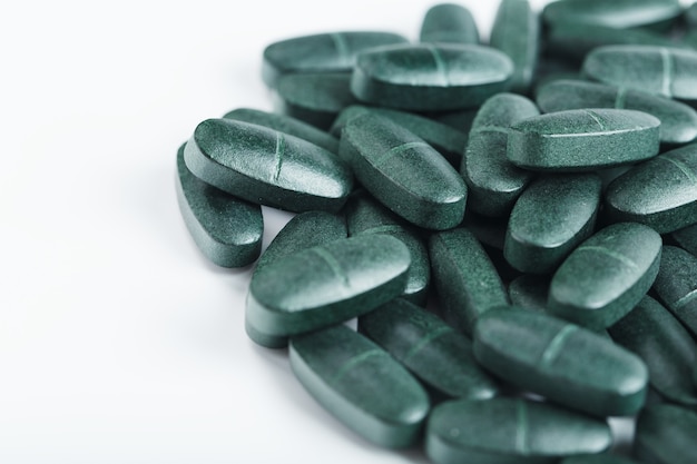 Compresse verdi con vitamine e spirulina per uomini su sfondo bianco. multivitaminici per la salute dell'uomo, isola, libera spazio