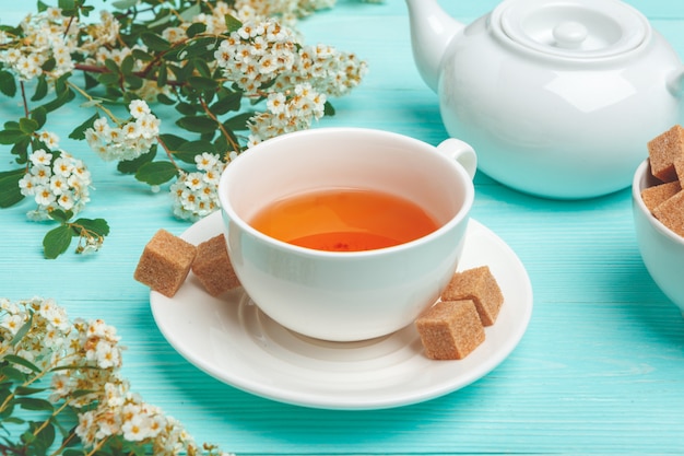 Green tea in a ceramic cup with branches of blossoming tree branches