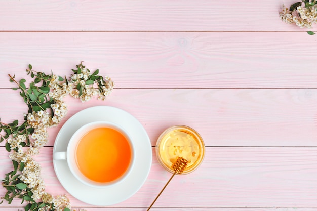 開花木の枝の枝を持つセラミックカップの緑茶