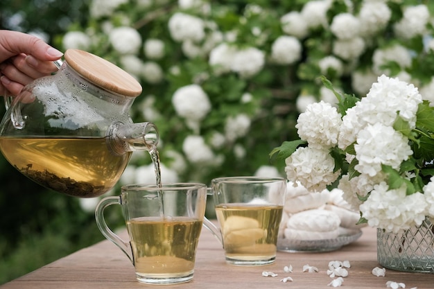 Green tea in a glass bowl on a wooden table against the backdrop of a blooming garden