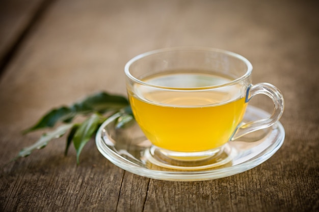 Green tea in glass cup and flowers on wooden table