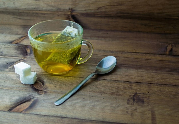 Foto tè verde in una tazza di vetro zucchero e un cucchiaio