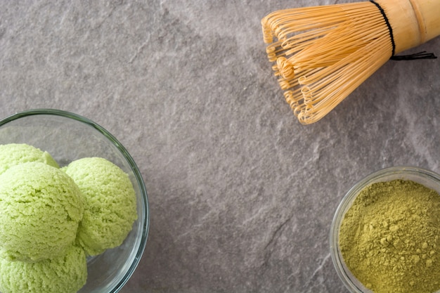 Green tea matcha ice cream scoops in crystal bowl on gray stone