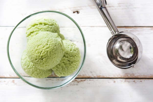 白い木製のテーブルの上のクリスタルボウルで抹茶抹茶アイスクリームスクープ