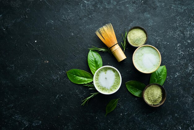 Green tea matcha latte art in a cup on a black stone background Asian drinks Top view