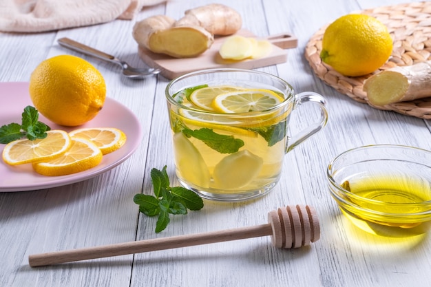 Photo green tea with lemon ginger and honey in a glass cup with oranges around on wooden table