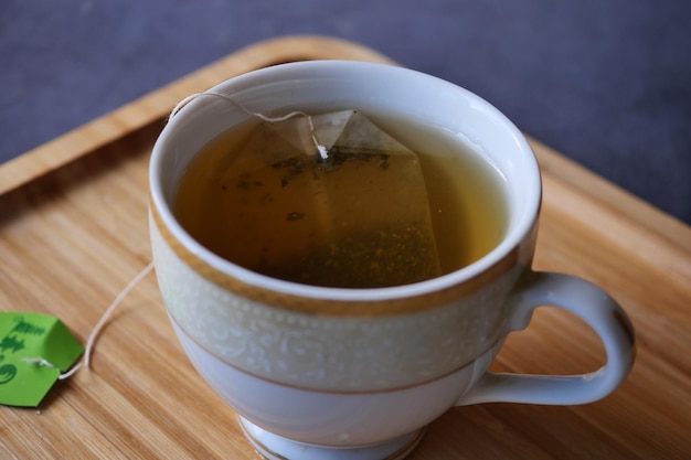 Green tea with tea bag on tiles background