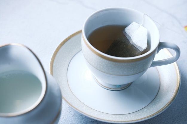 Green tea with tea bag on tiles surface