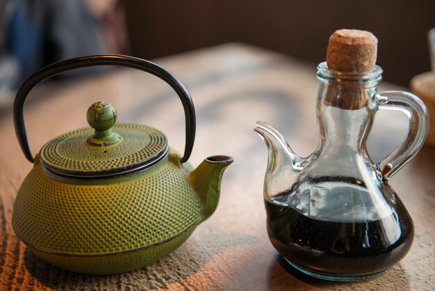 Green Teapot on the wooden table and soy pot at the table of the cafe