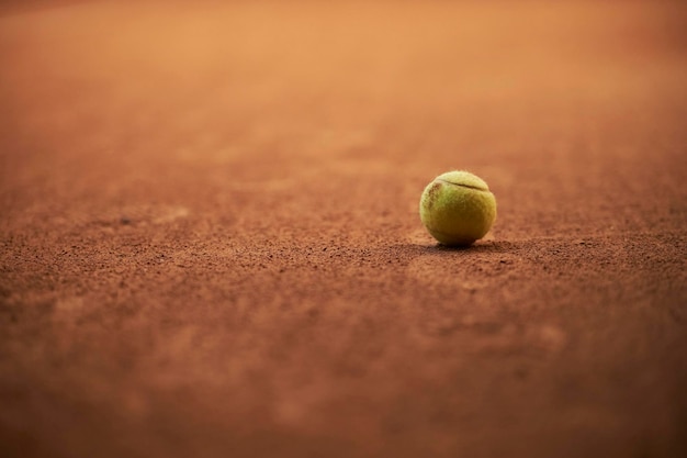 Green tennis ball on a brown tennis court background yellow
tennis ball on a clay court