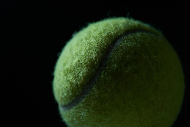 Фото Зеленый теннисный мяч на черном фоне