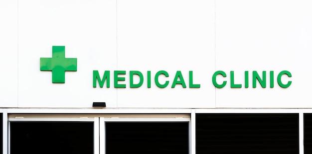 緑のテキスト建物に緑の十字アイコンが付いた診療所