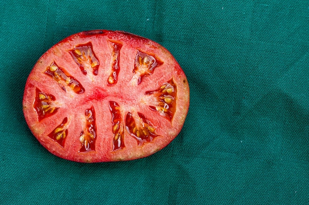 Photo green tomato halve on a red background close-up from above